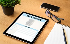 Dental insurance form on tablet next to notepad