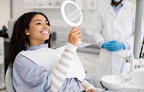 Woman smiling at reflection in handheld mirror