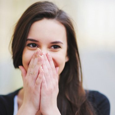 Smiling woman covering her mouth